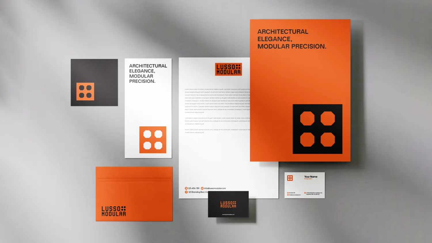 Lusso Modular stationery flat-lay showing an orange folder, letterhead, envelope, notecard and business cards, all carrying the module tile